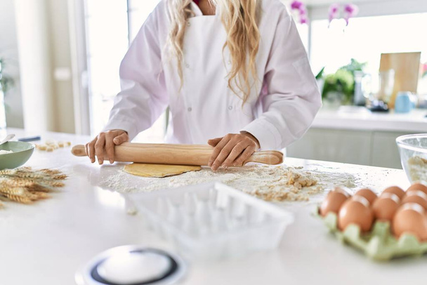 Молода жінка в уніформі готує тісто для макаронних виробів на кухні
 - Фото, зображення