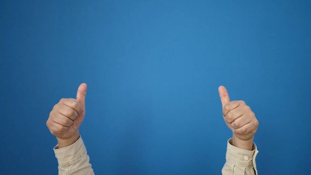 Junger hispanischer Mann macht Ok-Geste vor isoliertem blauen Hintergrund - Foto, Bild