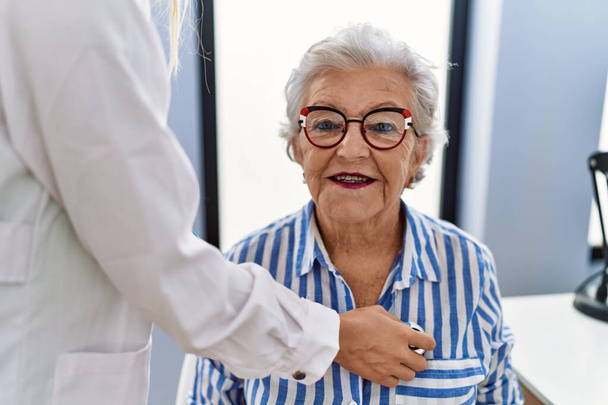 Vanhempi harmaahiuksinen nainen, jolla on lääkärin konsultaatio auskultoiva sydän klinikalla - Valokuva, kuva