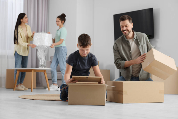 Happy family settling into new house and unpacking boxes. Moving day - Fotoğraf, Görsel