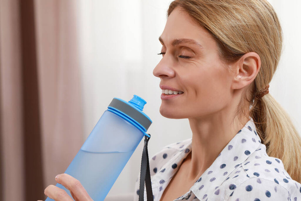 Happy woman with bottle of water in room - Photo, image