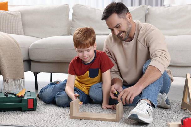 Father and son repairing shelf together at home - Фото, изображение