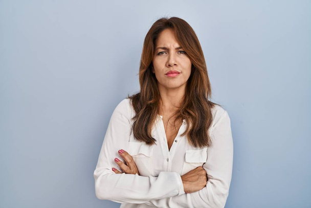 Hispanic woman standing over isolated background skeptic and nervous, disapproving expression on face with crossed arms. negative person.  - Photo, image