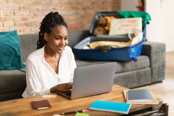 Pozitivní černá žena plánuje dovolenou cestování s notebookem, rezervace vstupenek nebo hotelový pokoj na webu, připravuje se na cestu do zahraničí, čtení turistického blogu on-line, volné místo - Fotografie, Obrázek