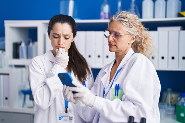 Dwie kobiety-naukowcy korzystające ze smartfona pracującego w laboratorium - Zdjęcie, obraz