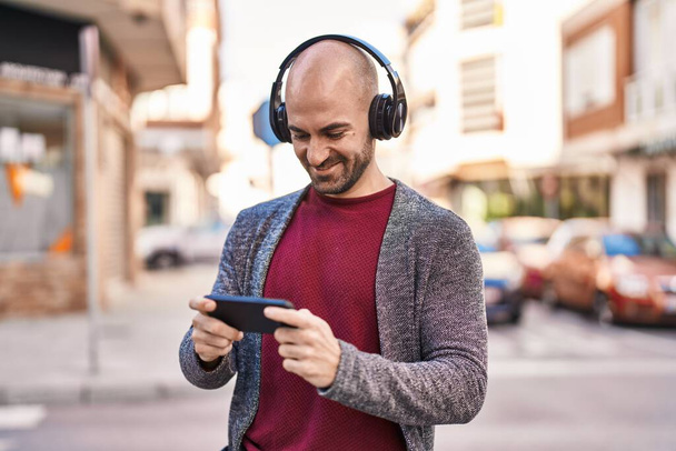 Fiatal férfi mosolygós magabiztos játszik videojáték az utcán - Fotó, kép