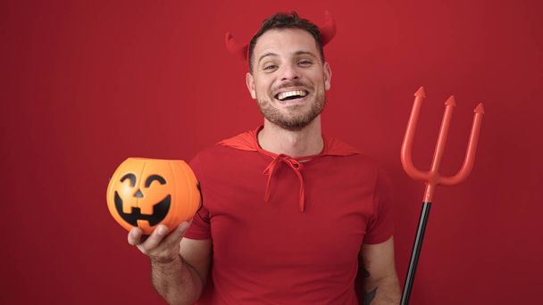 Young caucasian man smiling confident wearing devil costume over isolated red background - Foto, immagini