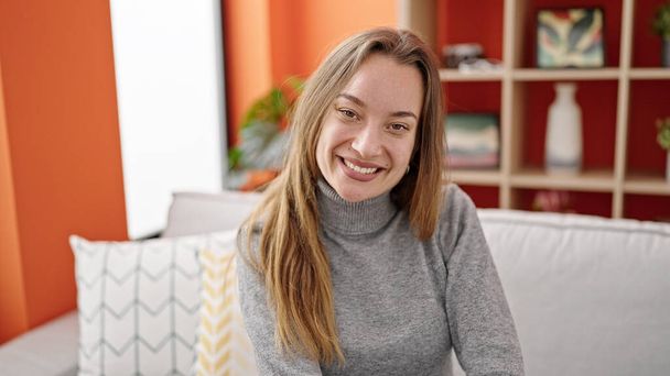 Young caucasian woman smiling confident sitting on sofa at home - Photo, Image