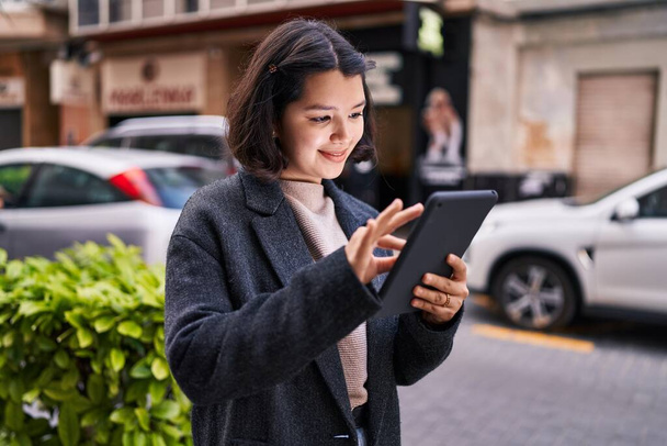 Jeune femme souriant confiant en utilisant touchpad à la rue - Photo, image