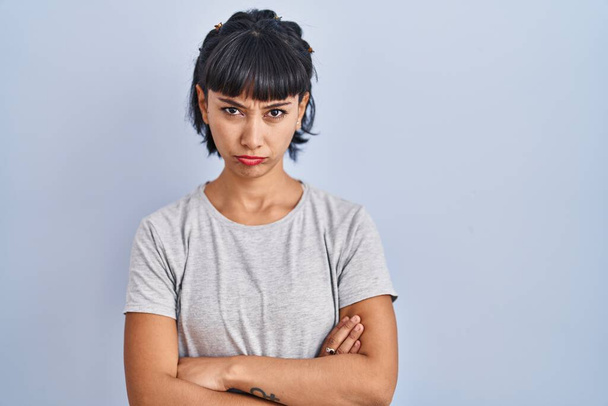 Young hispanic woman wearing casual t shirt over blue background skeptic and nervous, frowning upset because of problem. negative person.  - Valokuva, kuva