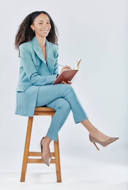 Planning, happy and a woman writing in a notebook isolated on a white background in a studio. Smile, creative and a girl in business sitting with a book for an agenda, ideas and notes on a backdrop. - Photo, Image