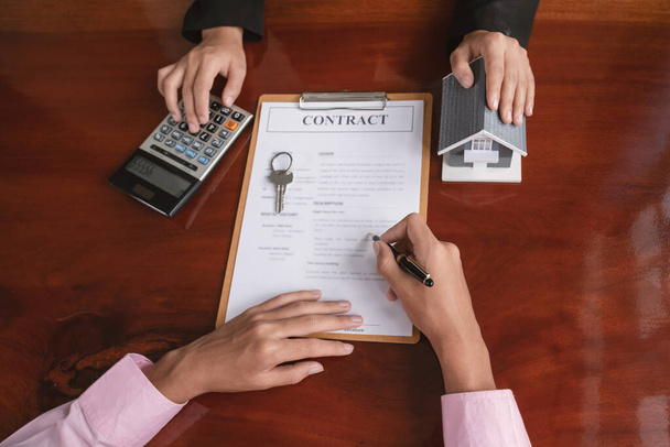 Handtekenen op contract nadat de makelaar verklaart het zakelijke contract, huur, aankoop, hypotheek, een lening, of woningverzekering aan de koper. - Foto, afbeelding