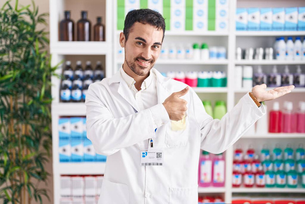 Bonito hispânico homem trabalhando na farmácia farmácia farmácia mostrando palma da mão e fazendo gesto ok com os polegares para cima, sorrindo feliz e alegre  - Foto, Imagem