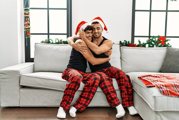 二つのヒスパニック男性カップル巨大お互いに座っていますによってクリスマス装飾で家 - 写真・画像