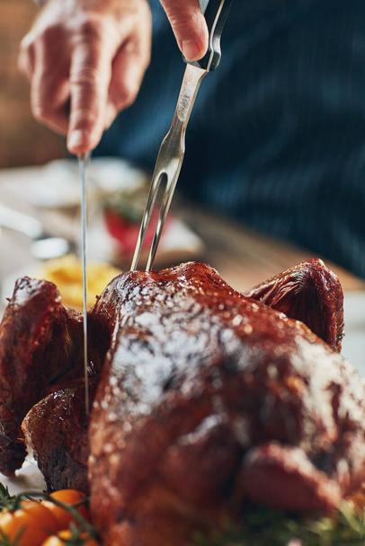 It makes for a showy main dish on every table. Closeup shot of a person cutting into a roasted turkey - Valokuva, kuva