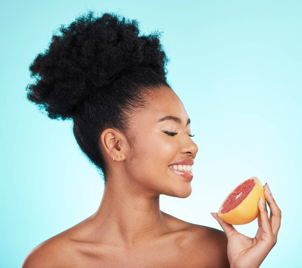 Grapefruit, skincare and woman smile with fruit for beauty, wellness and detox healthcare. Isolated, blue background and studio with a young female feeling happy from healthy food with vitamin c. - Photo, Image