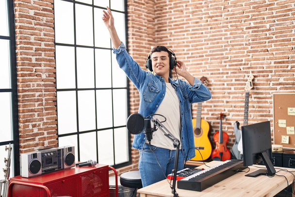 Young non binary man artist listening to music dancing at music studio - Φωτογραφία, εικόνα