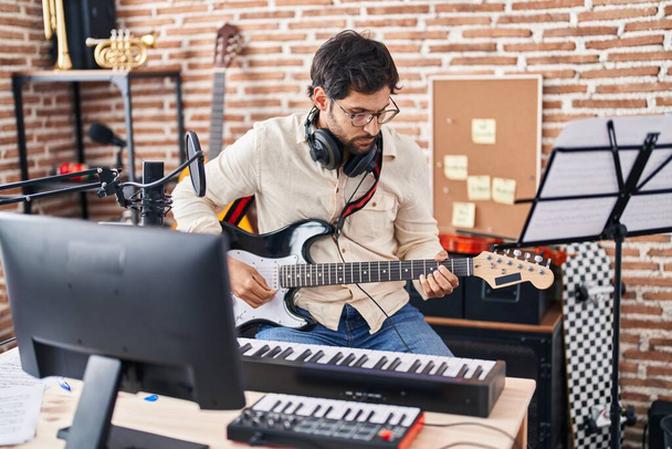 Jeune homme hispanique musicien jouant de la guitare électrique au studio de musique - Photo, image