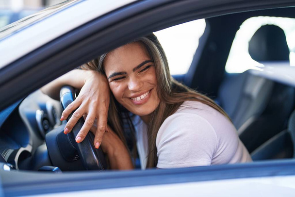 Mujer joven sonriendo confiado coche de conducción en la calle - Foto, Imagen