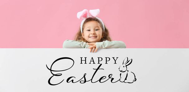 Little girl and poster with text HAPPY EASTER on pink background - Фото, изображение
