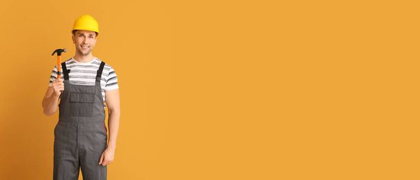 Όμορφος εργάτης με σφυρί σε πορτοκαλί φόντο με χώρο για κείμενο - Φωτογραφία, εικόνα