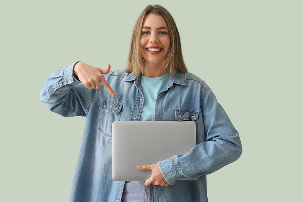Giovane donna in camicia di jeans con computer portatile su sfondo verde - Foto, immagini