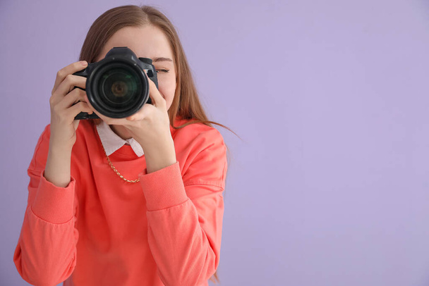 Joven fotógrafa con cámara profesional sobre fondo lila - Foto, Imagen
