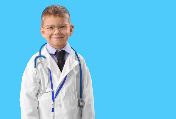 Cute little doctor in eyeglasses on blue background - Φωτογραφία, εικόνα