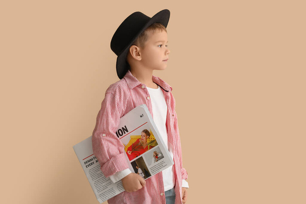 Cute little stylist with newspaper on beige background - Fotografie, Obrázek