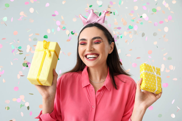 Mujer joven feliz con regalos de cumpleaños sobre fondo gris - Foto, imagen