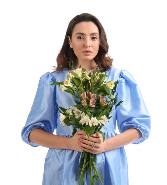 Νεαρή γυναίκα σε μπλε φόρεμα με λουλούδια alstroemeria σε λευκό φόντο - Φωτογραφία, εικόνα