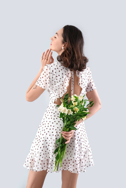 Young woman in dress with alstroemeria flowers on grey background - Foto, Imagen