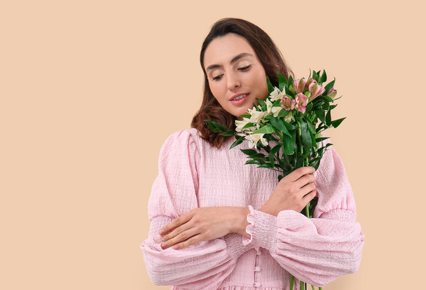Young woman in pink dress with alstroemeria flowers on beige background - Foto, Imagem