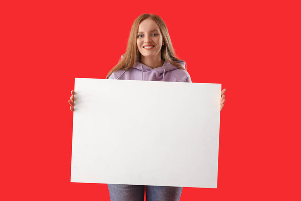 Beautiful woman with big blank poster on red background - Foto, afbeelding
