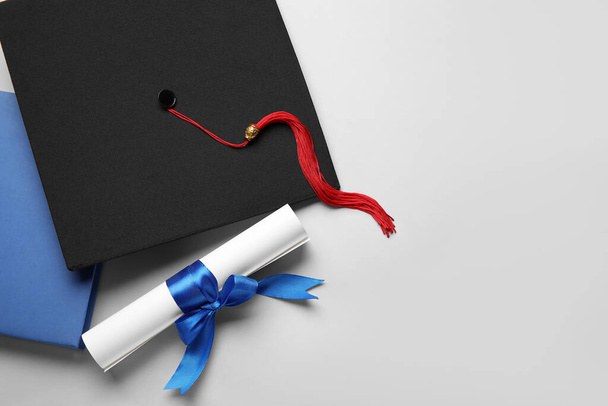 Diploma with blue ribbon, graduation hat and book on white background - Foto, Imagem
