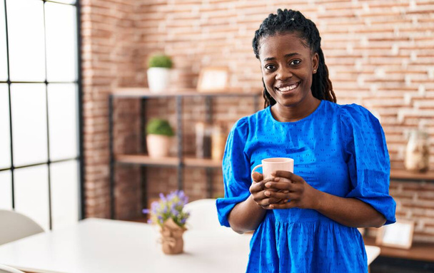 Африканська жінка - комерсант усміхається вдома і п "є каву. - Фото, зображення