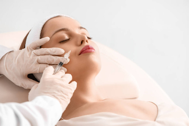 Young woman receiving filler injection  in beauty salon - Foto, imagen