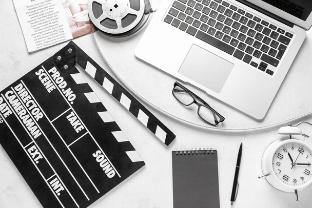 Movie clapper con bobina di film, occhiali e laptop su sfondo bianco - Foto, immagini
