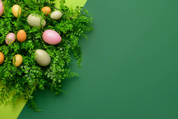 Easter eggs and plant leaves on green background - Foto, Imagen
