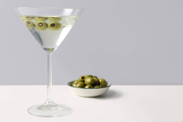Glass of martini and olives on light background - Photo, Image