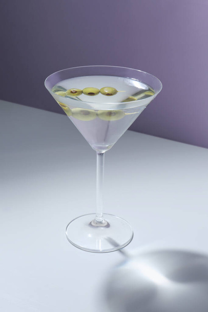 Glass of martini with olives on color background - Фото, изображение