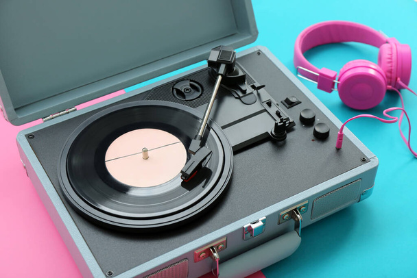 Συσκευή εγγραφής με δίσκο βινυλίου και ακουστικά στο φόντο χρώμα, closeup - Φωτογραφία, εικόνα