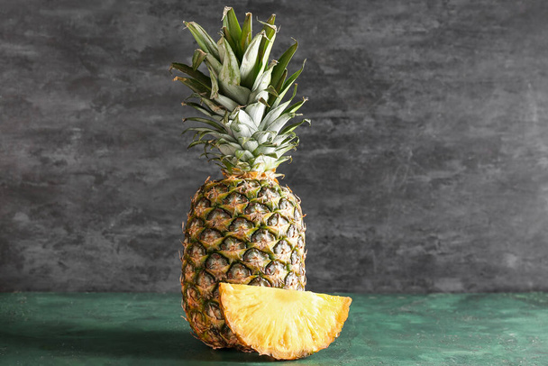 Fresh cut pineapples on color table near black wall - Фото, изображение