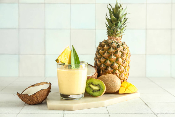 Lasi maukkaita ananas smoothie, kiivi ja kookos laatta pöydälle - Valokuva, kuva