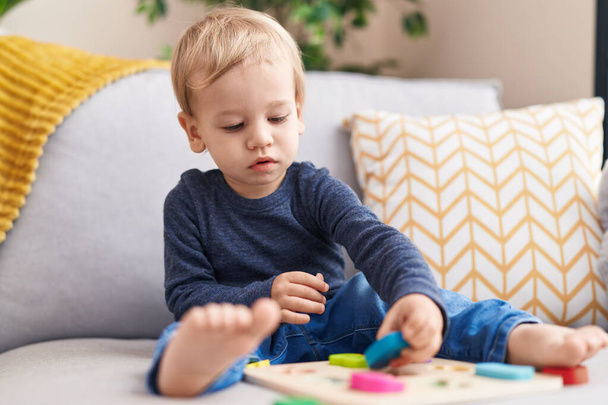 Entzückende blonde Kleinkind spielt mit Mathe-Spiel sitzt auf Sofa zu Hause - Foto, Bild