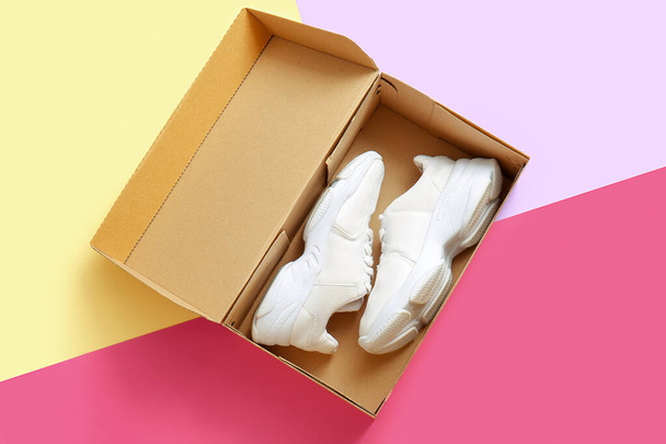 Caixa de papelão com sapatos esportivos em fundo de cor - Foto, Imagem