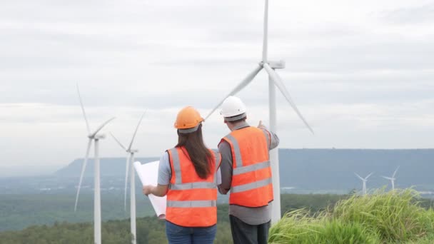 Engenheiros masculinos e femininos trabalhando em um parque eólico no topo de uma colina ou montanha no campo. Ideal progressivo para a futura produção de energia renovável e sustentável. - Filmagem, Vídeo