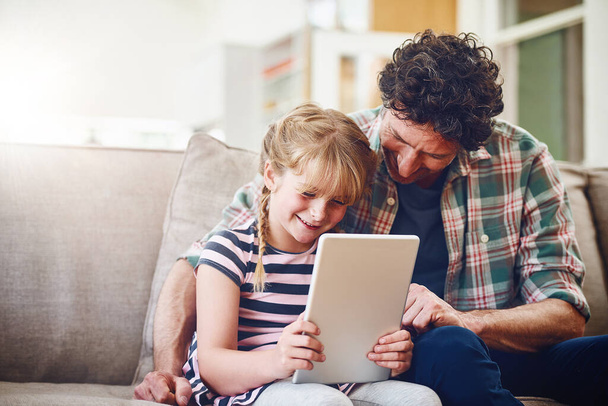 You sure know all the tricks to using this hey. a father and his little daughter using a digital tablet at home - Foto, Imagen