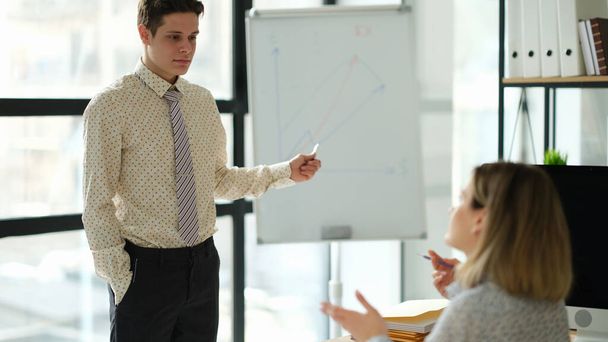 Бизнес-тренер показывает графики на доске ученику в офисе. Концепция бизнес образования - Фото, изображение