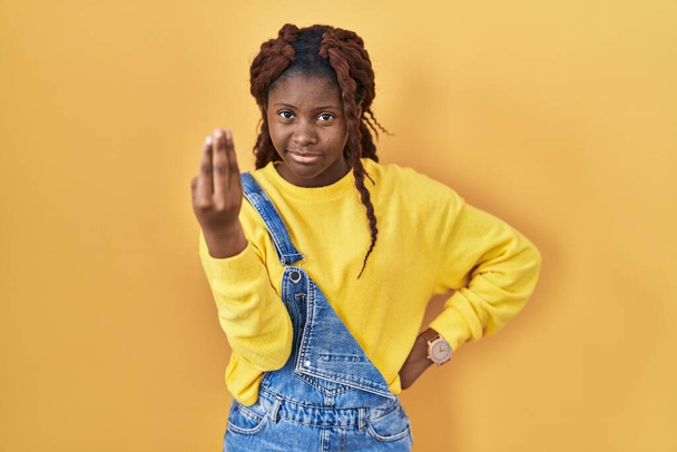 African woman standing over yellow background doing italian gesture with hand and fingers confident expression  - Фото, зображення